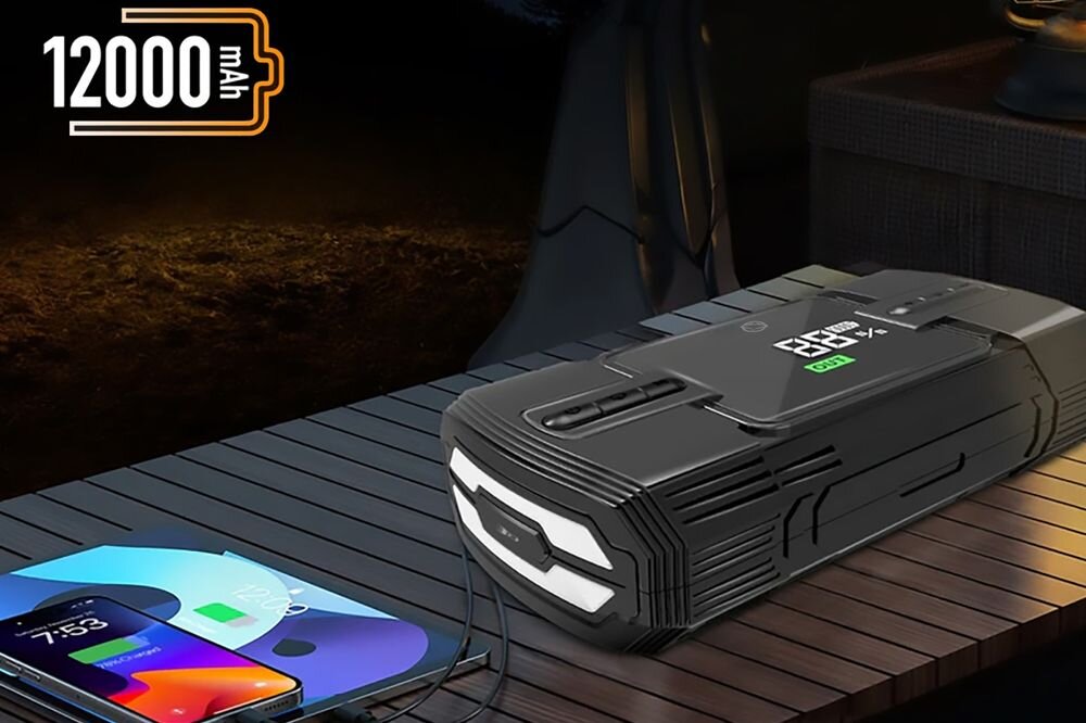 Manta MAJS001AP powerbank 12000mAh 44.4Wh do smartfona tabletu GPS w podróży, urządzenie leżace na stole obok smartfona