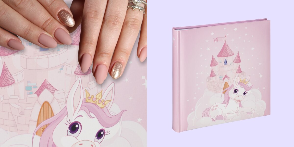 Album HAMA Joana Różowy (50 stron) Różowy album na zdjęcia dla dzieci z grafiką białego jednorożca w koronie na tle bajkowego zamku, prezentowany obok dłoni pokazującej skalę produktu.