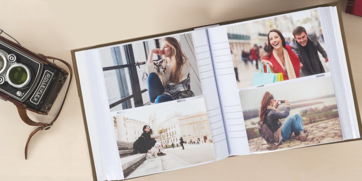 Album HAMA London Super Jumbo Białe Kartki Niebieski (80 stron) Otwarty album fotograficzny z białymi kartami i miejscem na opis, wypełniony kolorowymi zdjęciami, leżący obok zabytkowego aparatu Rolleiflex.