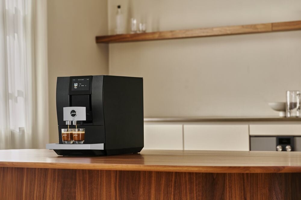 Ekspres Jura Z10 nalewający jednocześnie dwie kawy espresso do przezroczystych filiżanek na drewnianym blacie kuchennym