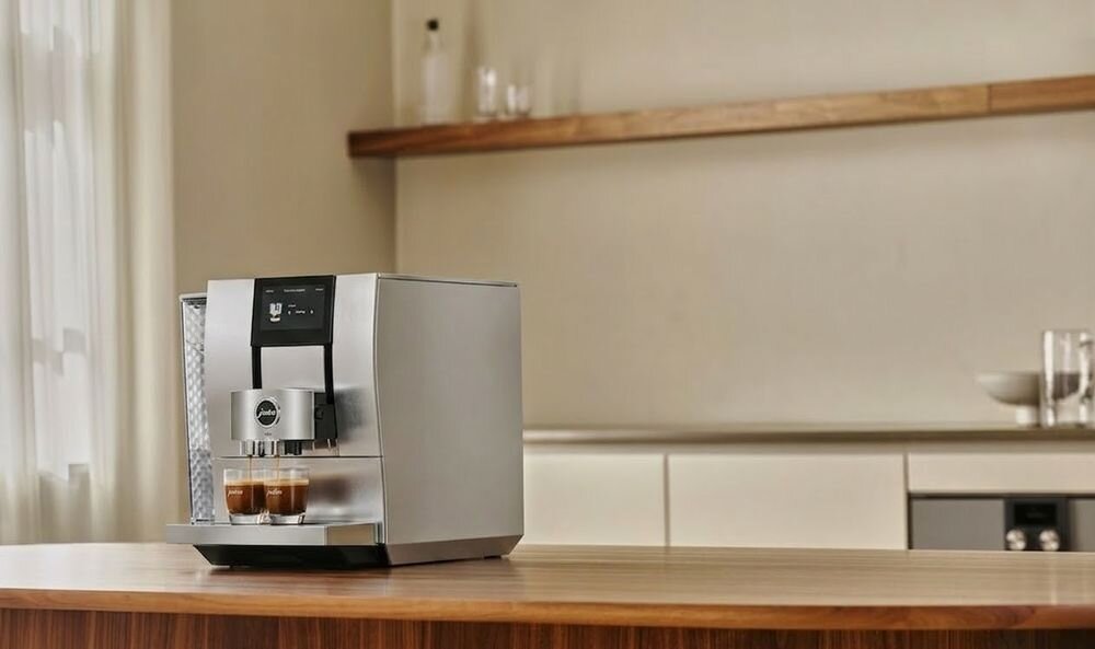 Ekspres Jura Z10 nalewający jednocześnie dwie kawy espresso do przezroczystych filiżanek na drewnianym blacie kuchennym