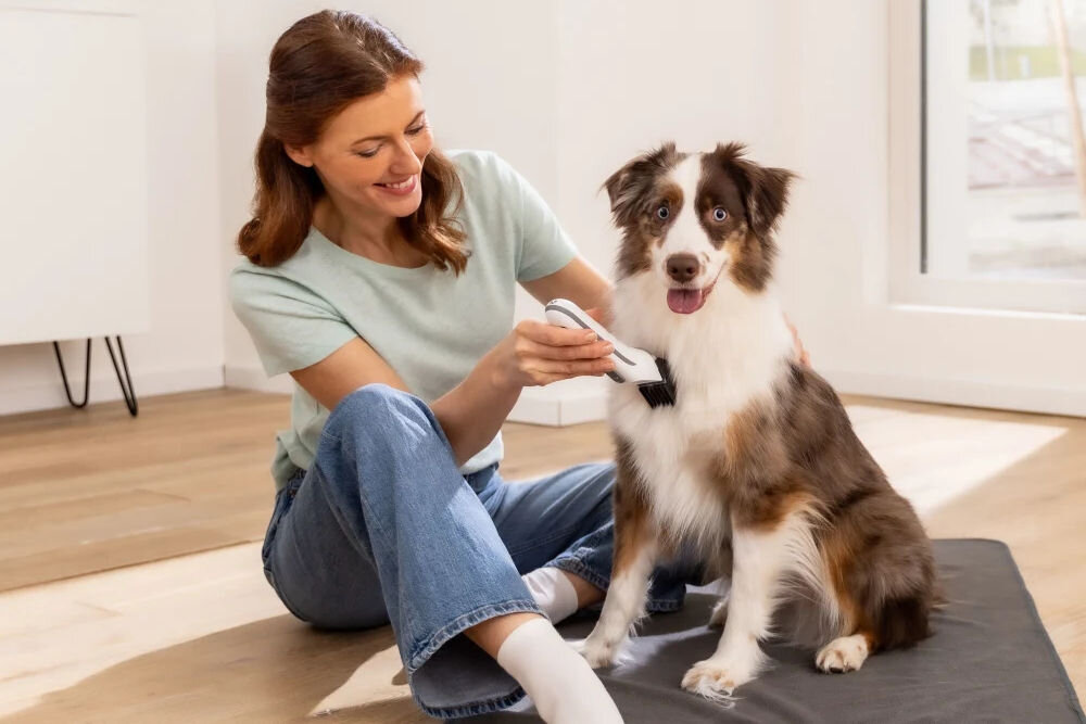 Trymer do strzyżenia zwierząt BEURER Fluffy uśmiechnięta osoba strzygąca psa siedzącego na podłodze