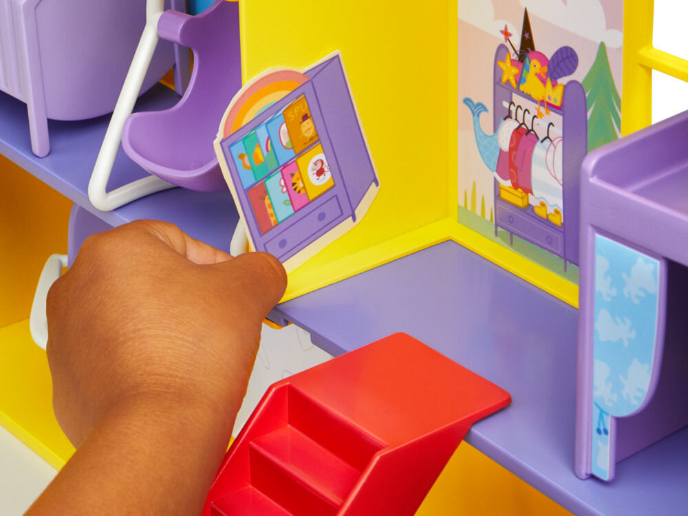 Zestaw figurek HASBRO Świnka Peppa Duży dom rodzinny Peppy G05085L0 Zbliżenie na dłoń dziecka przyklejającą naklejkę przedstawiającą szafę z zabawkami na żółtą ścianę zabawkowego domku Peppa Pig. Detal pokazuje możliwość personalizacji wnętrza zabawki przez użytkownika.