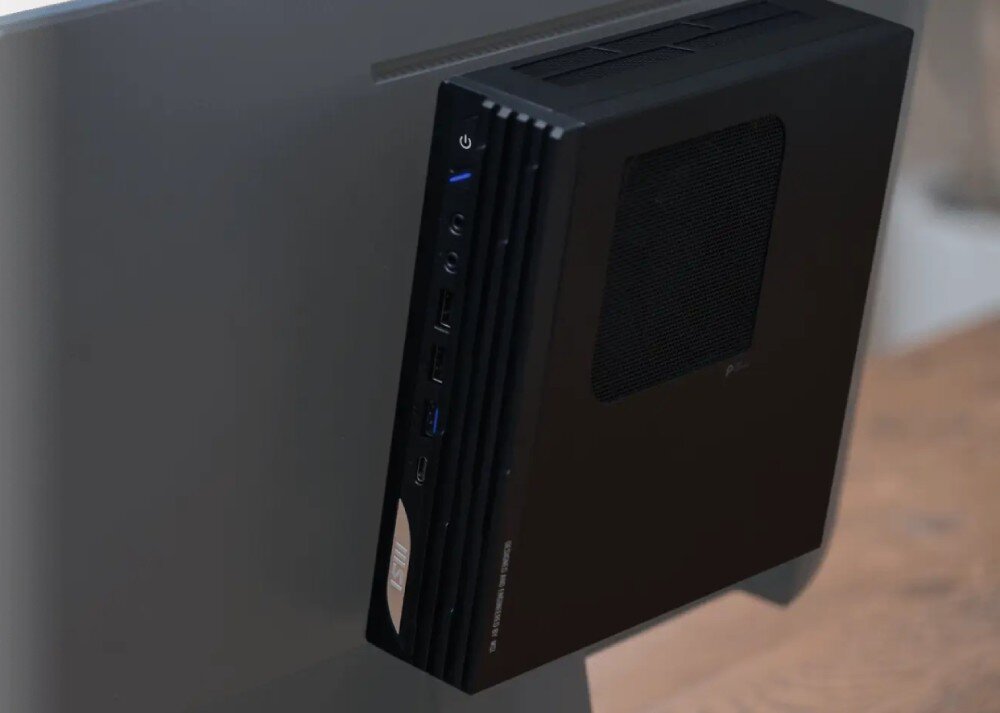 Komputer MSI Pro DP21 14M-889EU Czarny komputer typu mini PC zamontowany z tyłu obudowy szarego monitora komputerowego, montaż VESA, funkcja synchronizacji