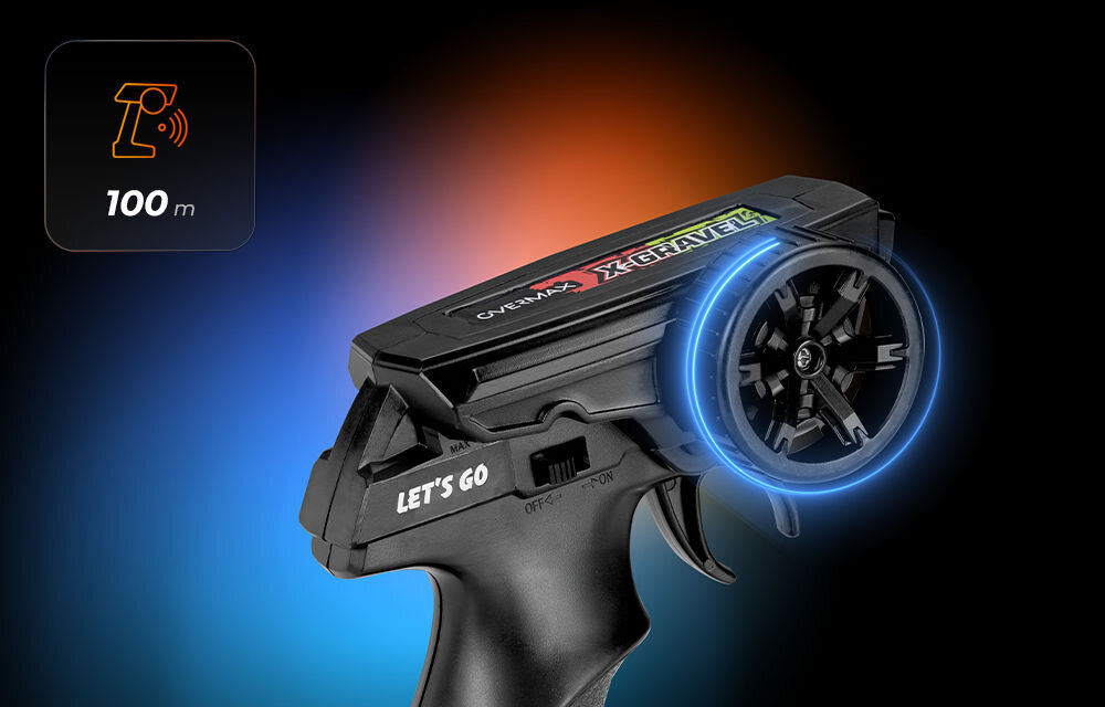 Samochód zdalnie sterowany OVERMAX X-Gravel Zbliżenie na czarny pilot zdalnego sterowania pistoletowego typu (Trigger/Wheel). Widoczne jest duże, czarne koło do sterowania, a na górze napis OVERMAX X-GRAVEL. Ikona w lewym górnym rogu wskazuje zasięg 100 m.