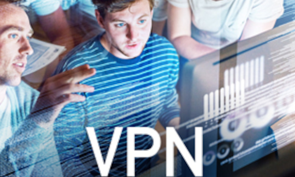 Na obrazie widać grupę osób patrzących na ekran komputera, na którym wyświetlane są wykresy i dane. Na pierwszym planie widoczny jest duży napis \'VPN\'.