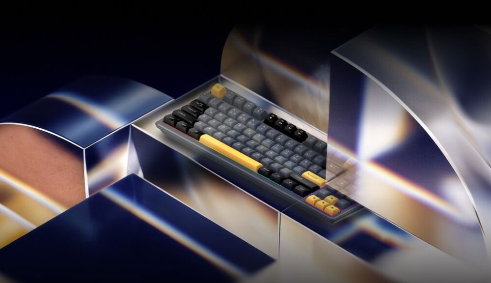 Obraz przedstawia klawiaturę z szarymi i żółtymi klawiszami, umieszczoną w futurystycznym, lustrzanym otoczeniu. Klawiatura ma wyraźnie zaznaczone klawisze funkcyjne w kolorze żółtym.
