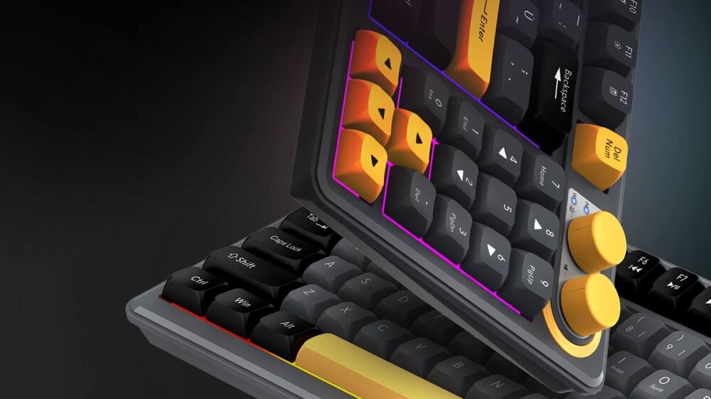 Obraz przedstawia klawiaturę z kolorowymi klawiszami, w tym pomarańczowymi i żółtymi, oraz dwoma żółtymi pokrętłami. Klawisze mają podświetlenie RGB, a na niektórych widoczne są napisy takie jak \'Enter\' i \'Shift\'.