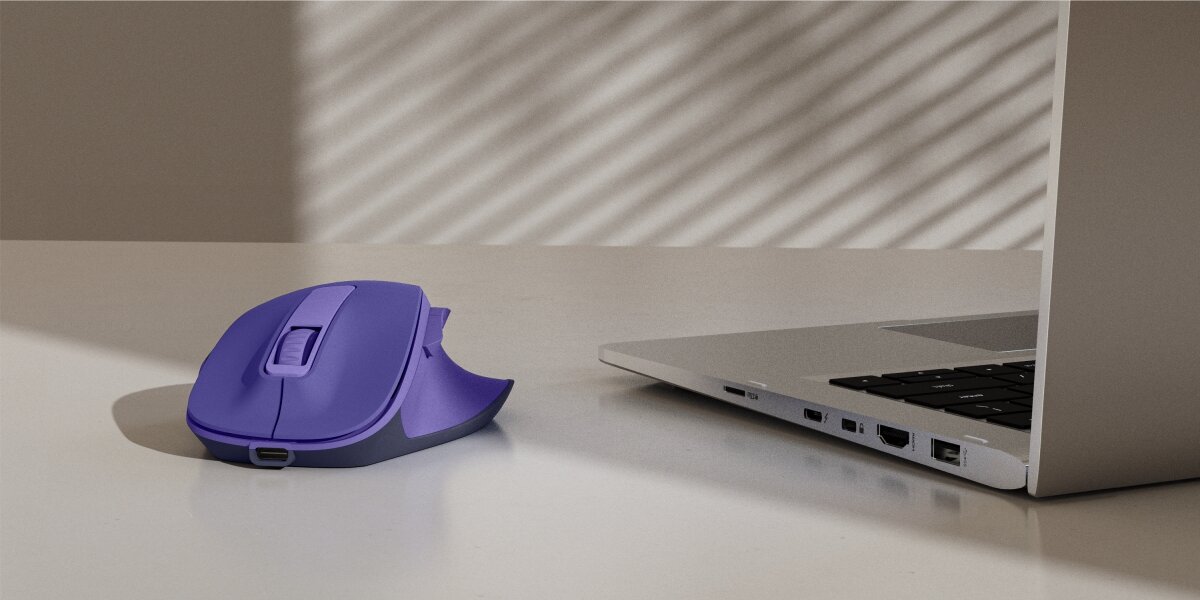 Ergonomiczna mysz bezprzewodowa Hama w kolorze fioletowym na biurku obok laptopa.