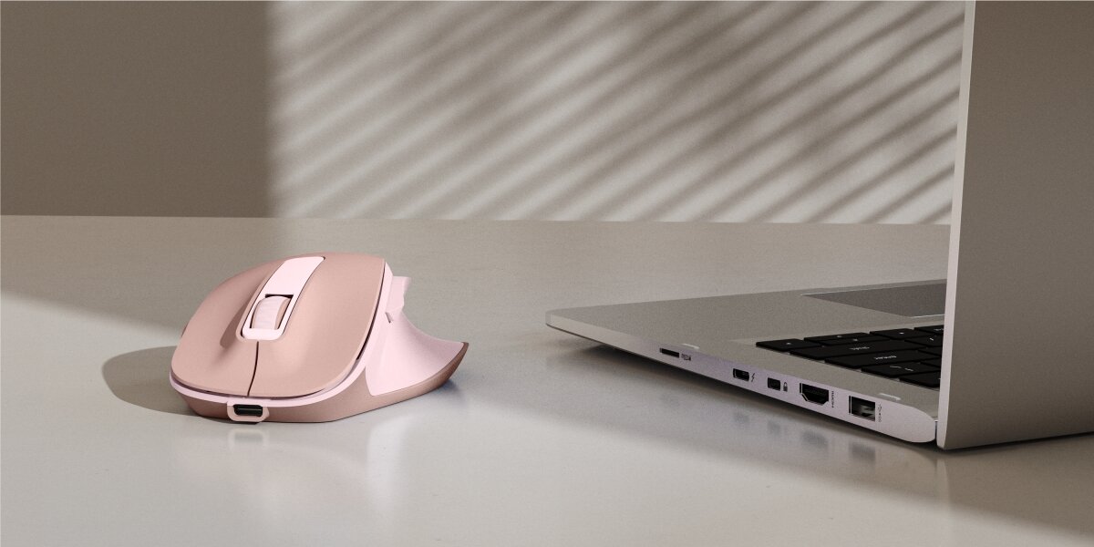Ergonomiczna mysz bezprzewodowa Hama w kolorze różowym na biurku obok laptopa.