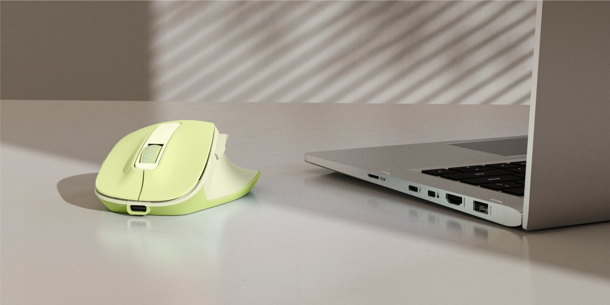 Ergonomiczna mysz bezprzewodowa Hama w kolorze limonkowym na biurku obok laptopa.