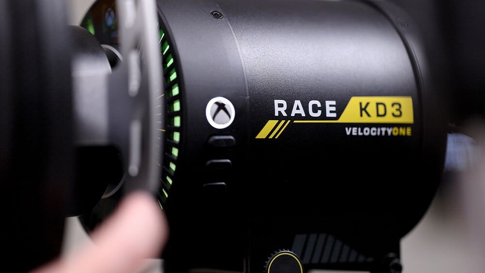 Kierownica Turtle Beach Velocity OneRace KD3 Bardzo bliskie zbliżenie na bok bazy kierownicy z napisem RACE KD3 VelocityOne oraz podświetlonym wskaźnikiem możliwość konfiguracji silnik K: Drive obrót kierownicy zakres regulowane pedały łopatki zmiany biegów układ Force Feedback