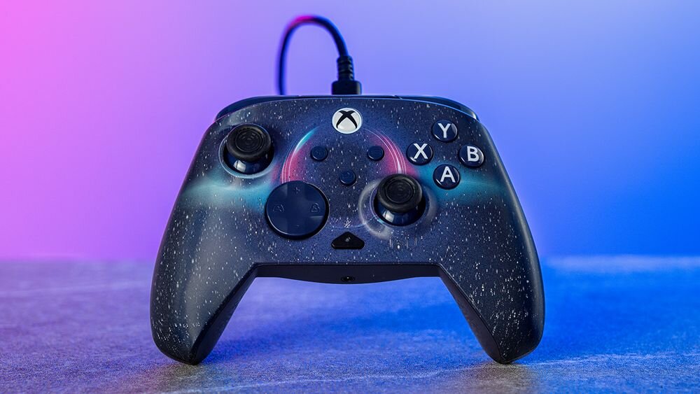 Kontroler TURTLE BEACH Xbox Rematch Advanced Dark Cosmos TBC-2404-05 Frontowy widok pada Dark Cosmos na ciemnym blacie, oświetlony nastrojowym fioletowo-niebieskim światłem soczewkowe wykończenie indywidualny styl