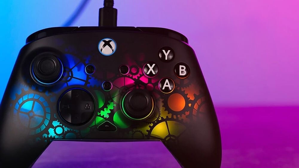 Kontroler TURTLE BEACH Xbox Afterglow Ignite TBC-2006-05 Frontowy widok pada Afterglow Ignite na fioletowo-niebieskim tle, prezentujący wielokolorowe podświetlenie RGB motywu zębatych kół sprawne działanie dopasowanie stylu rozgrywki krótkie spusty hallotronowe dwustopniowa regulacja ustawienie czułości spustów realizm gry