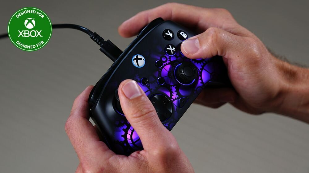 Kontroler TURTLE BEACH Xbox Afterglow Ignite TBC-2006-05 Dłonie gracza na kontrolerze Afterglow Ignite z fioletowym podświetleniem; w rogu widoczny logotyp Designed for Xbox specjalna tekstura wygodnie leży w dłoni