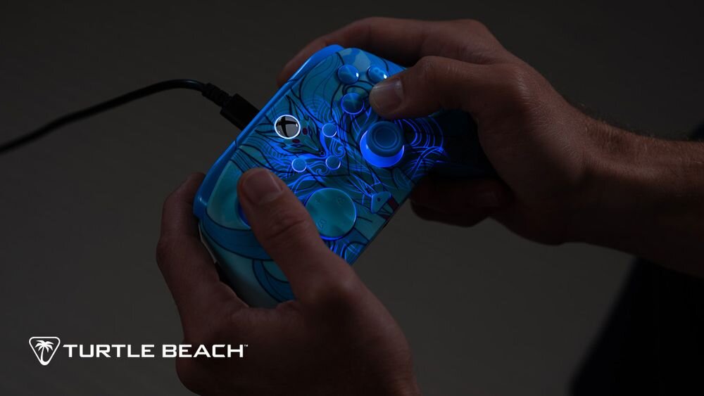 Kontroler TURTLE BEACH Xbox Rematch Advanced Blue Kitsune TBC-2004-25 Zbliżenie na dłonie trzymające kontroler Turtle Beach Blue Kitsune w ciemnym pomieszczeniu z włączonym niebieskim podświetleniem obudowy
