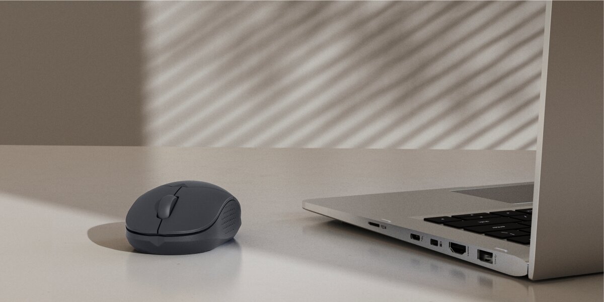 Ciemnoszara mysz bezprzewodowa Hama na biurku obok laptopa, idealna do pracy.