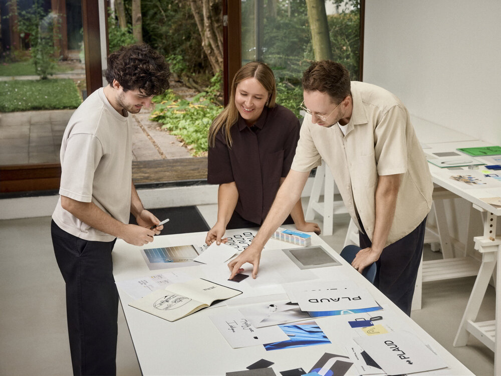 PLAUD Note PRO profesjonalne notatki podsumowania decyzje informacje, osoby stojące przy stole, dyktafon leżący na stole