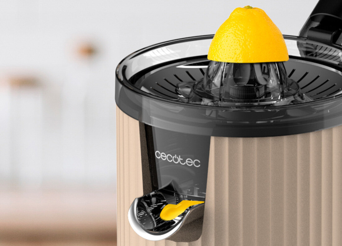 Wyciskarka do cytrusów w beżowym kolorze z logo \'cecotec\' na obudowie. Na górze urządzenia znajduje się połówka cytryny.