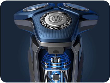 Zbliżenie na głowicę golarki z trzema okrągłymi ostrzami i widocznymi elementami technologicznymi w dolnej części. Golarka ma ciemnoniebieski kolor z metalicznymi akcentami.