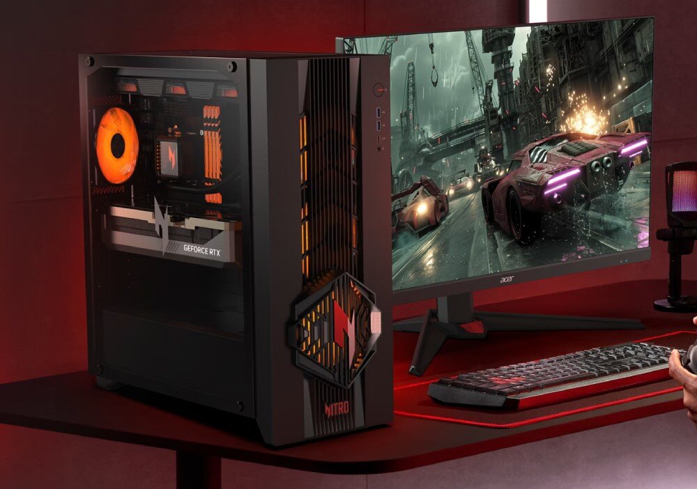 Komputer ACER Nitro 70 N70X3D-100 Stanowisko gracza z czarnym komputerem stacjonarnym, monitorem wyświetlającym scenę z gry wyścigowej, klawiaturą oraz podkładką na biurku w czerwonym oświetleniu, pamięć RAM, dysk