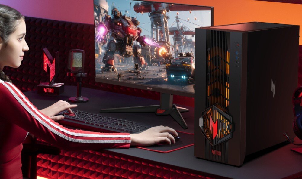 Komputer ACER Nitro 70 N70X3D-100 Osoba siedząca przy biurku i korzystająca z komputera stacjonarnego oraz monitora, na którym widać scenę walki robotów, w otoczeniu czerwonych paneli wygłuszających na ścianie, wygląd, szklany bok, podświetlenie