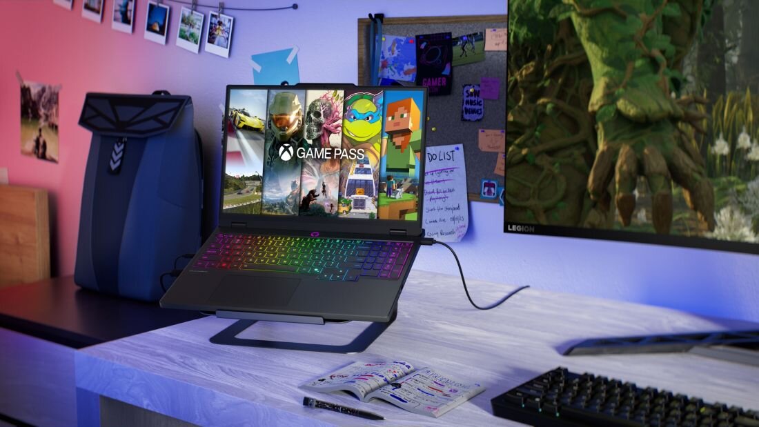  Czarny laptop Lenovo Legion na biurku obok kolorowej klawiatury mechanicznej z podświetleniem RGB, słuchawek gamingowych, notatnika i naklejek gier, pokazujący kompletne stanowisko gracza. - Opis serii Legion 5 