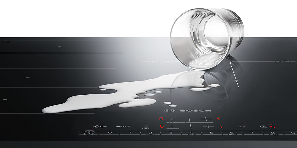PŁYTA BOSCH PXL811H26E Na zdjęciu widać szklaną płytę indukcyjną Bosch, na której przewrócona szklanka rozlała mleko po gładkiej powierzchni. Rozlana ciecz podkreśla łatwość czyszczenia płyty oraz odporność panelu sterowania na przypadkowe zabrudzenia automatyczne wyłączenie zapis ustawień łatwe czyszczenie szybkie przywracanie