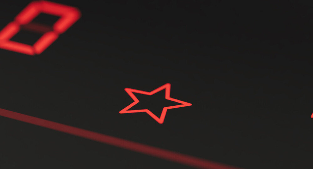 PŁYTA BOSCH PXL811H26E Na zdjęciu pokazano zbliżenie symbolu podświetlonej na czerwono gwiazdki na czarnej szklanej powierzchni panelu sterowania płyty grzewczej. Obok widać fragment cyfry, co sugeruje obecność elektronicznego wyświetlacza z dodatkowymi funkcjami Przycisk Ulubione optymalne wybrane ustawienia moc czas szybkie gotowanie integracja Home Connect komfort