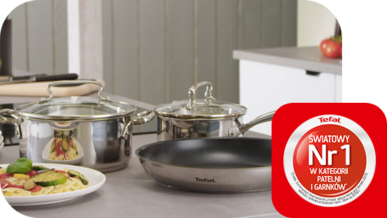 Na blacie kuchennym znajdują się trzy garnki i patelnia marki Tefal. Obok widoczna jest czerwona naklejka z napisem \'Tefal Światowy Nr 1 w kategorii patelni i garnków\'.