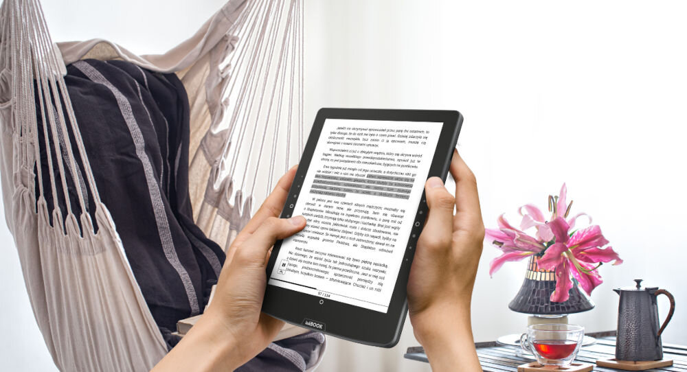Czytnik e-booków INKBOOK Solaris Color 6 cali, Podświetlany ekran, Wi-Fi Niebieski czytnik trzymany w dłoniach w tle pokój jasna ściana obsługa popularnych plików Wi-Fi Bluetooth Google Dysk Send2inkBOOK swoboda wyboru metody transferu
