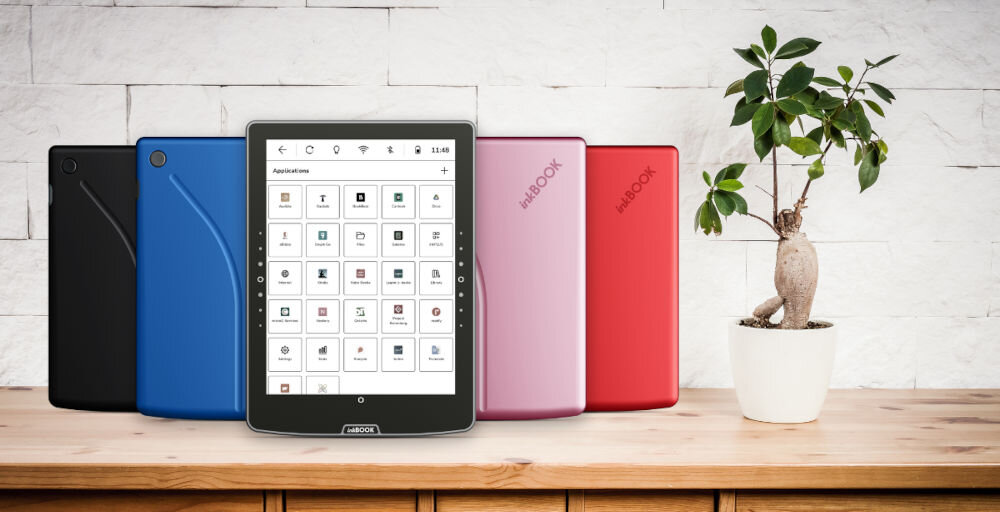 Czytnik e-booków INKBOOK Solaris Color 6 cali, Podświetlany ekran, Wi-Fi Żółty czytnik w różnych wersjach kolorystycznych na drewnianym blacie obok roślina w doniczce jasna ceglana ściana dostęp do znanych platform swoboda wyboru