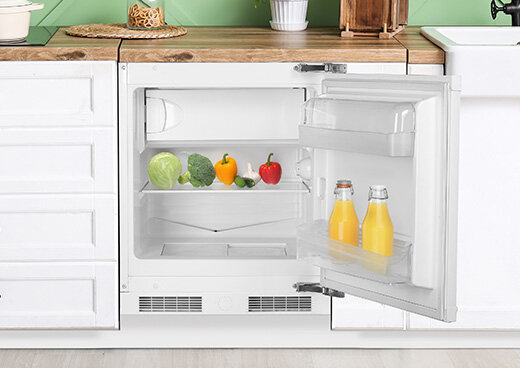 Otwarta lodówka w zabudowie kuchennej.