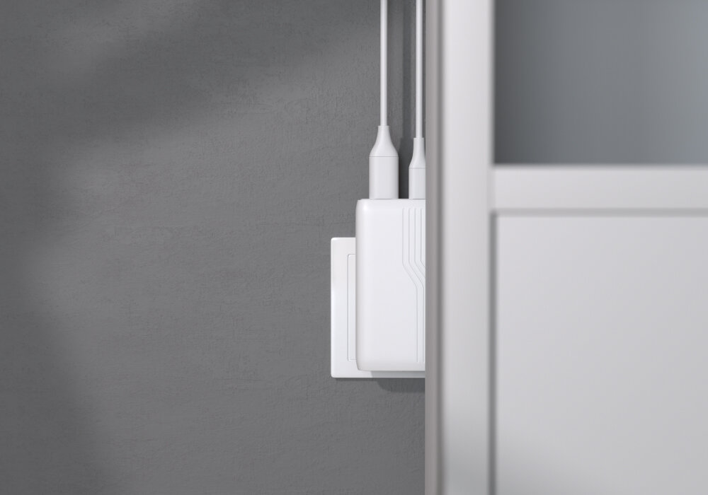 ALLITY ATC-02-65WAC portom USB-A i USB-C szybkiego ładowania QC i PD sprzętów mobilnych ładować dwa urządzenia w tym samym czasie - ładowarka podłączona do gniazdka ściennego za szafką, widoczne dwa kable
