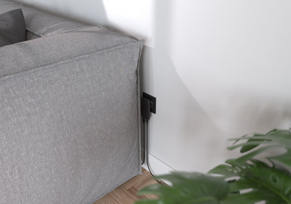 ALLITY ATC-02-65WAC Allity płaskiej konstrukcji portom ładowania umieszczonym od spodu - ładowarka podłączona do gniazdka za kanapą, widoczne dwa kable wychodzące w stronę mebli