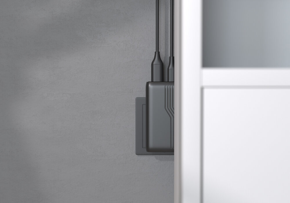 ALLITY ATC-02-65WAC portom USB-A i USB-C szybkiego ładowania QC i PD sprzętów mobilnych ładować dwa urządzenia w tym samym czasie - ładowarka podłączona do gniazdka ściennego za szafką, widoczne dwa kable