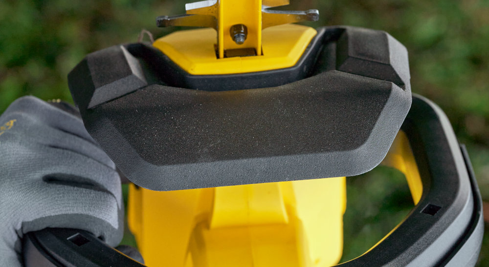 Nożyce do żywopłotu STANLEY SFMCHT655B-XJ 550mm 20V akumulatorowe zbliżenie na osłonę rozmazane zielone tło osłona chroni dłonie przed odpadkami i gałęziami zwiększa bezpieczeństwo swobodnie manewrować minimalizując ryzyko skaleczeń