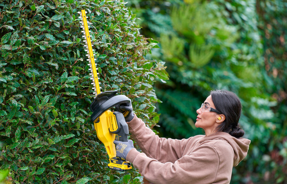 Nożyce do żywopłotu STANLEY SFMCHT650D1-QW 500mm 20V akumulatorowe ogród osoba przycina żywopłot w tle inne rośliny pielęgnacja żywopłotu przycinanie żywopłotu zadbany ogród
