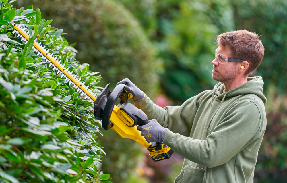 Nożyce do żywopłotu STANLEY SFMCHT655M1-QW 550mm 20V akumulatorowe ogród osoba przycina żywopłot w tle inne rośliny pielęgnacja żywopłotu przycinanie żywopłotu zadbany ogród