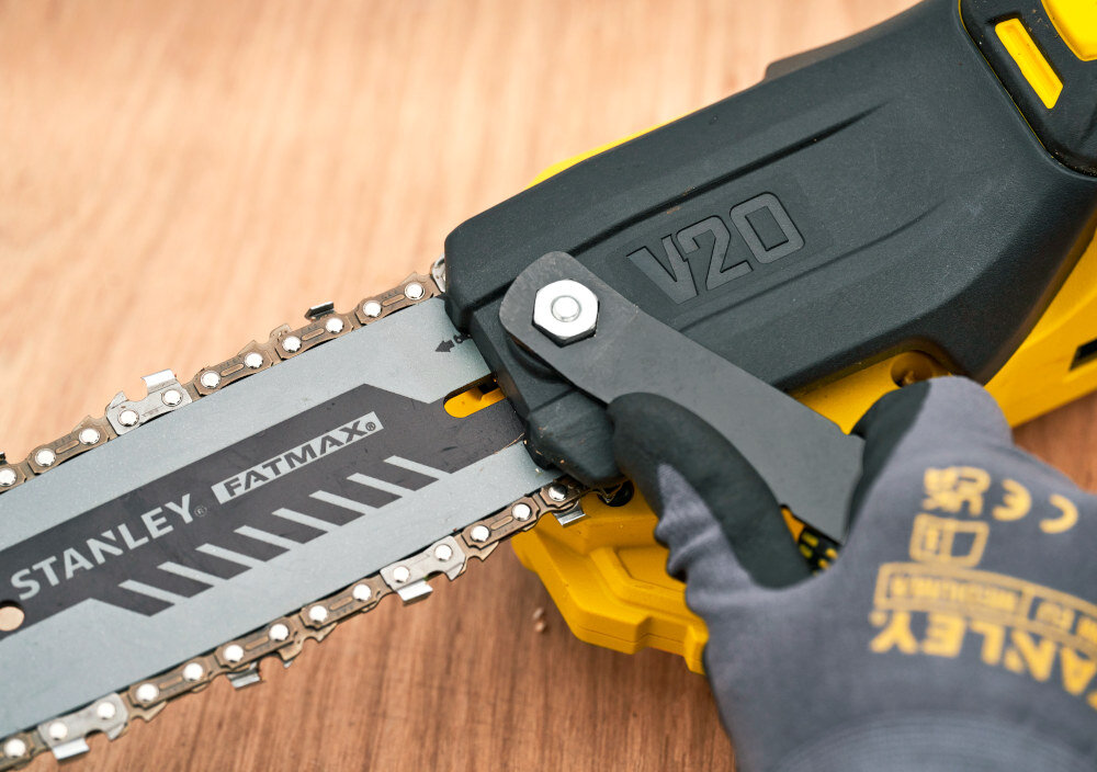 Piła akumulatorowa STANLEY SFMCPS720B-XJ SOLO drewniany blat piła na blacie osoba napina łańcuch za pomocą klucza boczny system napinania łańcucha oparty na śrubach precyzyjne ustawienie napięcia dołączony klucz przechowywany w obudowie narzędzia