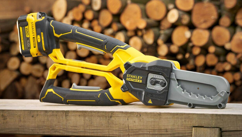 Sekator do gałęzi akumulatorowy STANLEY SFMCPS515M1-QW drewniany blat na blacie leży sekator w tle drewniane kłody drzewa sprawne cięcie zadbane drzewa i krzewy skuteczność uniwersalność