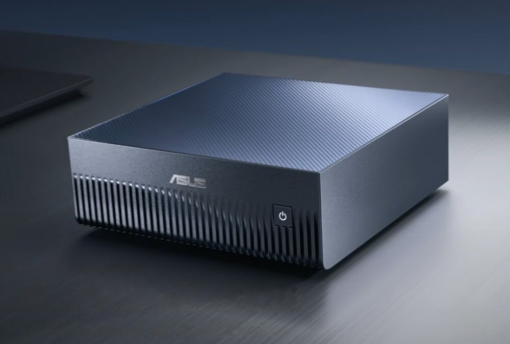 Komputer ASUS Ascent GX10 Srebrna, żebrowana obudowa komputera typu mini PC na abstrakcyjnym tle pełnym niebieskich i fioletowych, rozmytych świateł oraz drobnych kropek układających się w falę