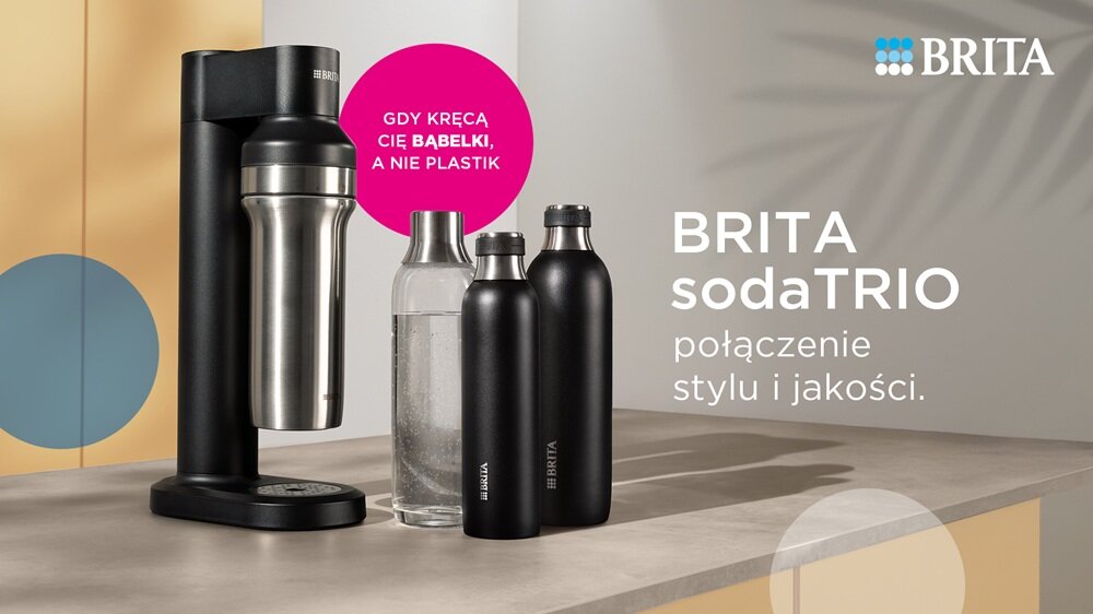 Na blacie stoi urządzenie do gazowania wody oraz trzy butelki, w tym dwie czarne i jedna przezroczysta. Widoczny tekst: \'Gdy kręcą cię bąbelki, a nie plastik\', \'BRITA sodaTRIO połączenie stylu i jakości\', oraz logo \'BRITA\'.