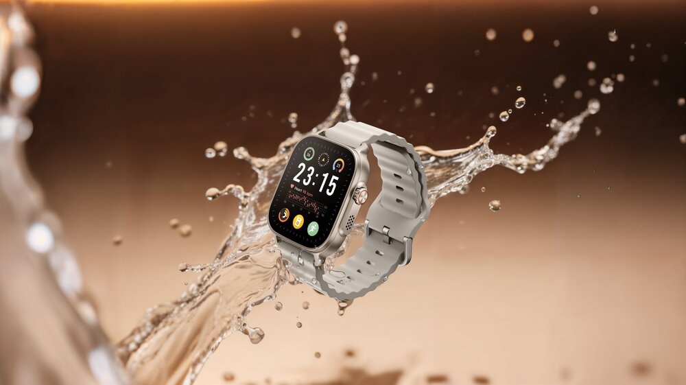 Smartwatch w srebrnym kolorze zanurzony w wodzie, z wyświetlaczem pokazującym godzinę 23:15 oraz kilka ikon aplikacji.