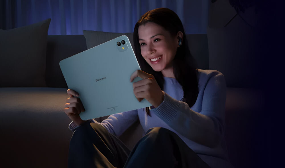 Tablet BLACKVIEW Link 8 12.7 cala 12/256 GB Wi-Fi Niebieski Uśmiechnięta kobieta siedząca na podłodze w słabo oświetlonym pokoju, oglądająca coś na jasnoniebieskim tablecie Blackview VidGen przekształcanie zdjęć w filmowe klipy Soundle kształtowanie dźwięku tworzenie muzyki z AI