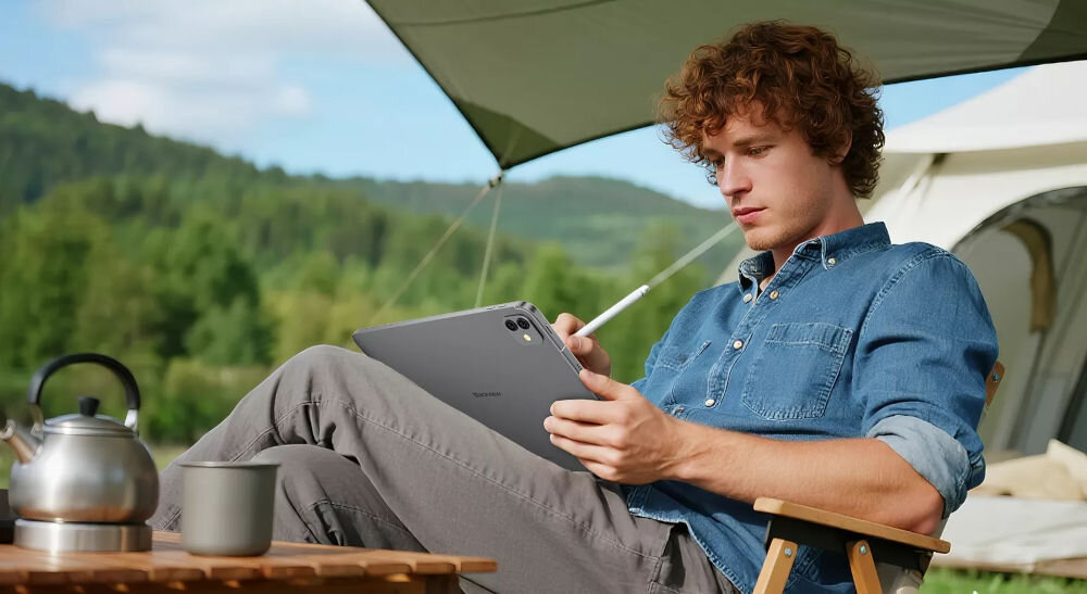 Tablet BLACKVIEW Link 8 12.7 cala 6/256 GB Wi-Fi Fioletowy Mężczyzna siedzący na krześle kempingowym przed namiotem, używający szarego tabletu Blackview z rysikiem RAM możliwość rozszerzenia praca na wielu programach jednocześnie wielozadaniowość komfort pracy