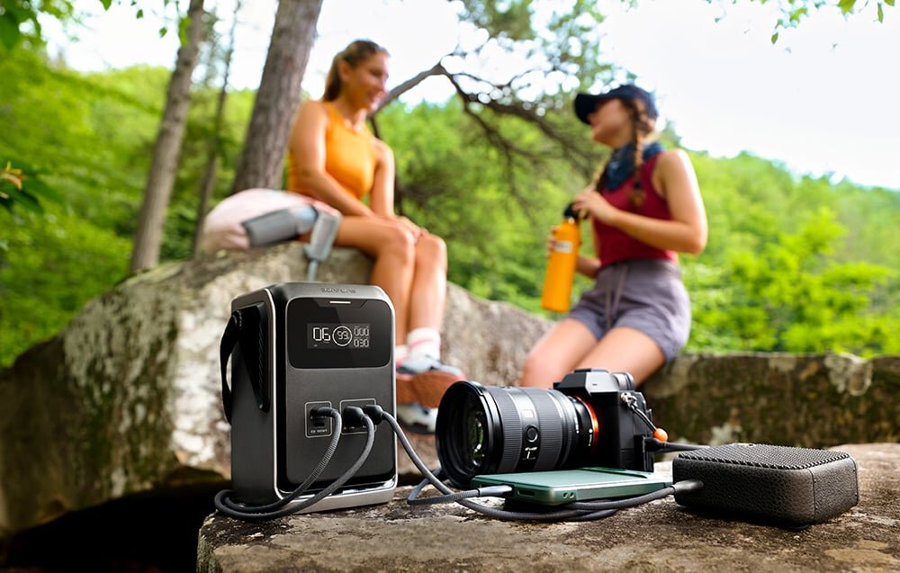 Stacja zasilania ECOFLOW Trail 200 DC, USB-C, szybkie, laptopy, PD,  EcoFlow River 2 Pro wśród drzew i liści w lesie: kompaktowa stacja z wyświetlaczem 90%, portami i uchwytem na ziemi obok smartfona.