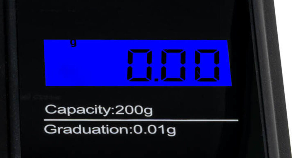 Wyświetlacz elektroniczny pokazuje wartość 0.00 g na niebieskim tle. Pod spodem widnieje napis \'Capacity: 200g Graduation: 0.01g\'.