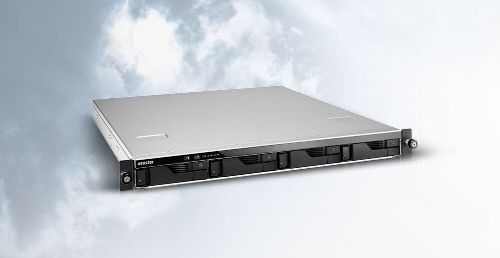 Serwer plików ASUSTOR AS6504RS Widok na srebrną obudowę serwera typu rack w orientacji trzy czwarte na tle błękitnego nieba z białymi chmurami. Urządzenie posiada cztery czarne kieszenie na dyski z przodu oraz logotyp producenta w lewym górnym rogu panelu frontowego