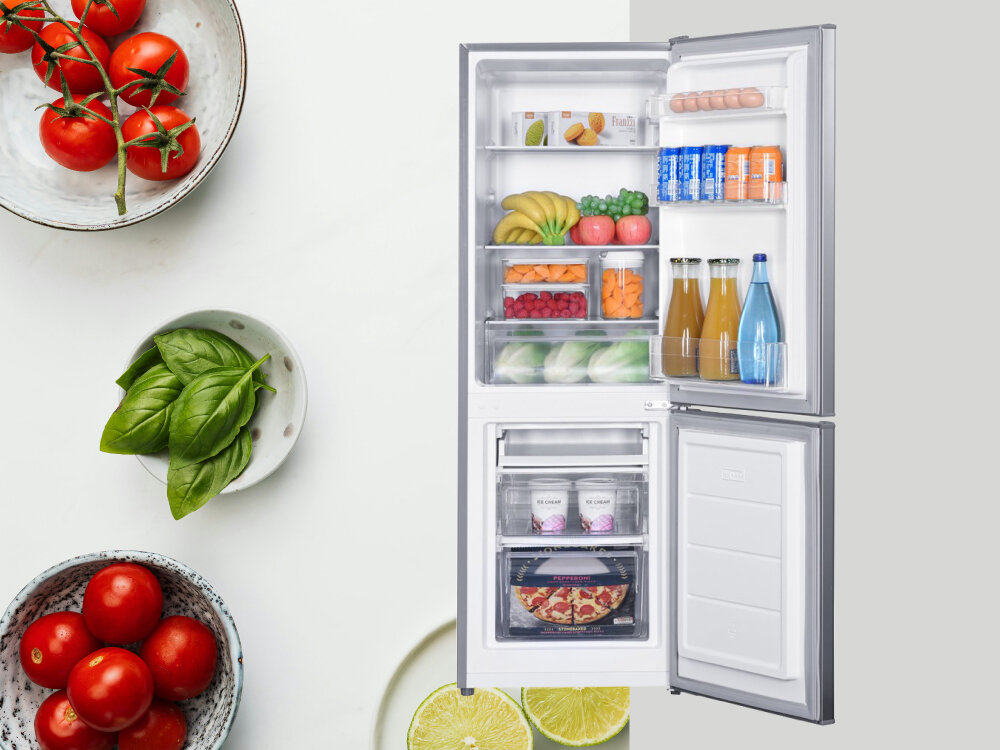 Lodówka ETA ETA385690010C Otwarta lodówka z widoczną zawartością pokazana na tle kompozycji kulinarnej z pomidorami, bazylią i cytrusami, podkreślającej świeżość przechowywanych produktów mechaniczne sterowanie regulowany termostat automatyczne odszranianie wpuszczane uchwyty regulowane nóżki wygoda